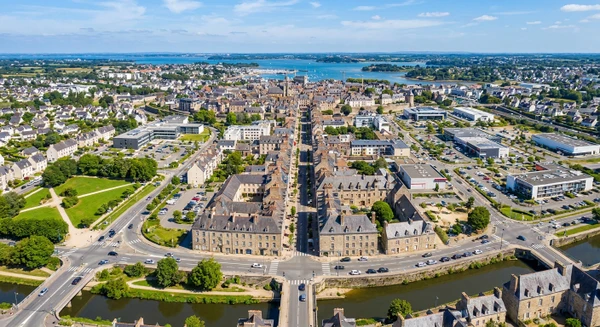 Vue a&eacute;rienne ou paysag&egrave;re de la ville de Vannes avec ses quartiers r&eacute;sidentiels et commerciaux, montrant le tissu urbain et les environs, en journ&eacute;e avec une bonne luminosit&eacute; naturelle. L'image doit transmettre l'accessibilit&eacute; et la proximit&eacute; de l'entreprise pour les habitants de cette zone g&eacute;ographique. Aucun texte, logo ou filigrane ne doit &ecirc;tre visible.