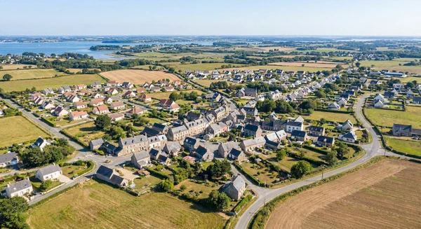 Vue a&eacute;rienne ou paysag&egrave;re de Plougoumelen montrant son tissu urbain, ses quartiers r&eacute;sidentiels, ses routes d'acc&egrave;s et ses alentours ruraux caract&eacute;ristiques de la Bretagne sud, photographi&eacute;e en journ&eacute;e avec une bonne luminosit&eacute; naturelle. L'image doit transmettre l'accessibilit&eacute; et la proximit&eacute; de Plougoumelen comme base d'intervention de l'entreprise. Photographie r&eacute;aliste de haute qualit&eacute; professionnelle sans texte, logo ou filigrane visible.