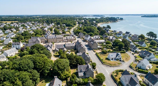 Vue a&eacute;rienne ou paysag&egrave;re de la commune d'Arradon en Bretagne sud, photographi&eacute;e en journ&eacute;e avec une bonne luminosit&eacute; naturelle. L'image doit montrer le tissu urbain, les quartiers r&eacute;sidentiels, les routes d'acc&egrave;s et les alentours caract&eacute;ristiques de la r&eacute;gion. Elle doit transmettre l'accessibilit&eacute; et la proximit&eacute; d'Arradon comme zone d'intervention de l'entreprise. Photographie r&eacute;aliste de haute qualit&eacute; professionnelle sans texte, logo ou filigrane visible.