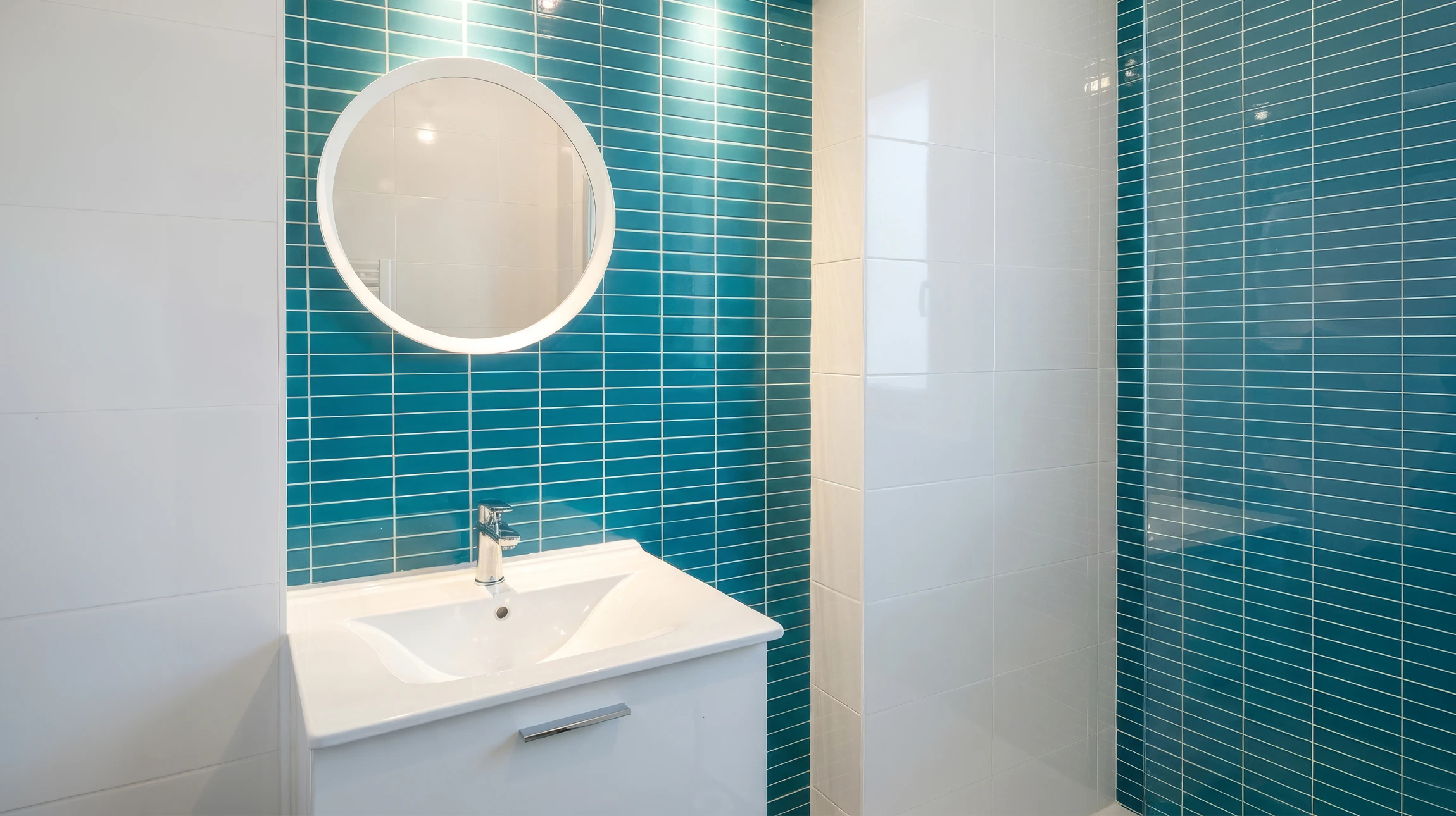 Salle de bain compacte avec WC suspendu à commande de chasse murale, douche à l'italienne carrelée en mosaïque bleu turquoise, robinet douchette chromée et pommeau de douche encastré
