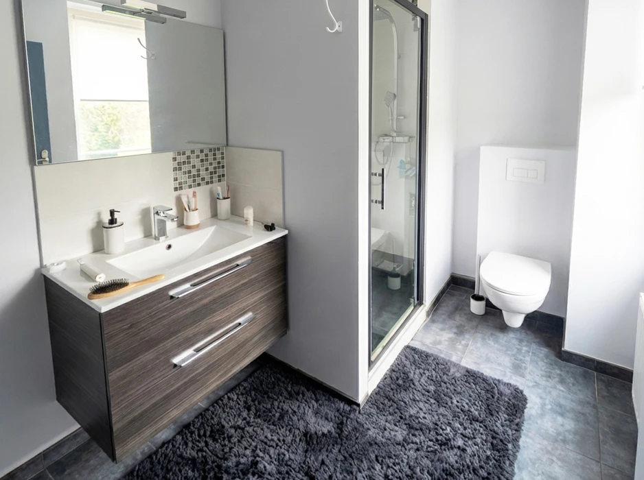 Salle de bain moderne et épurée avec meuble vasque suspendu en bois foncé, plan vasque blanc intégré, robinetterie chromée, miroir mural