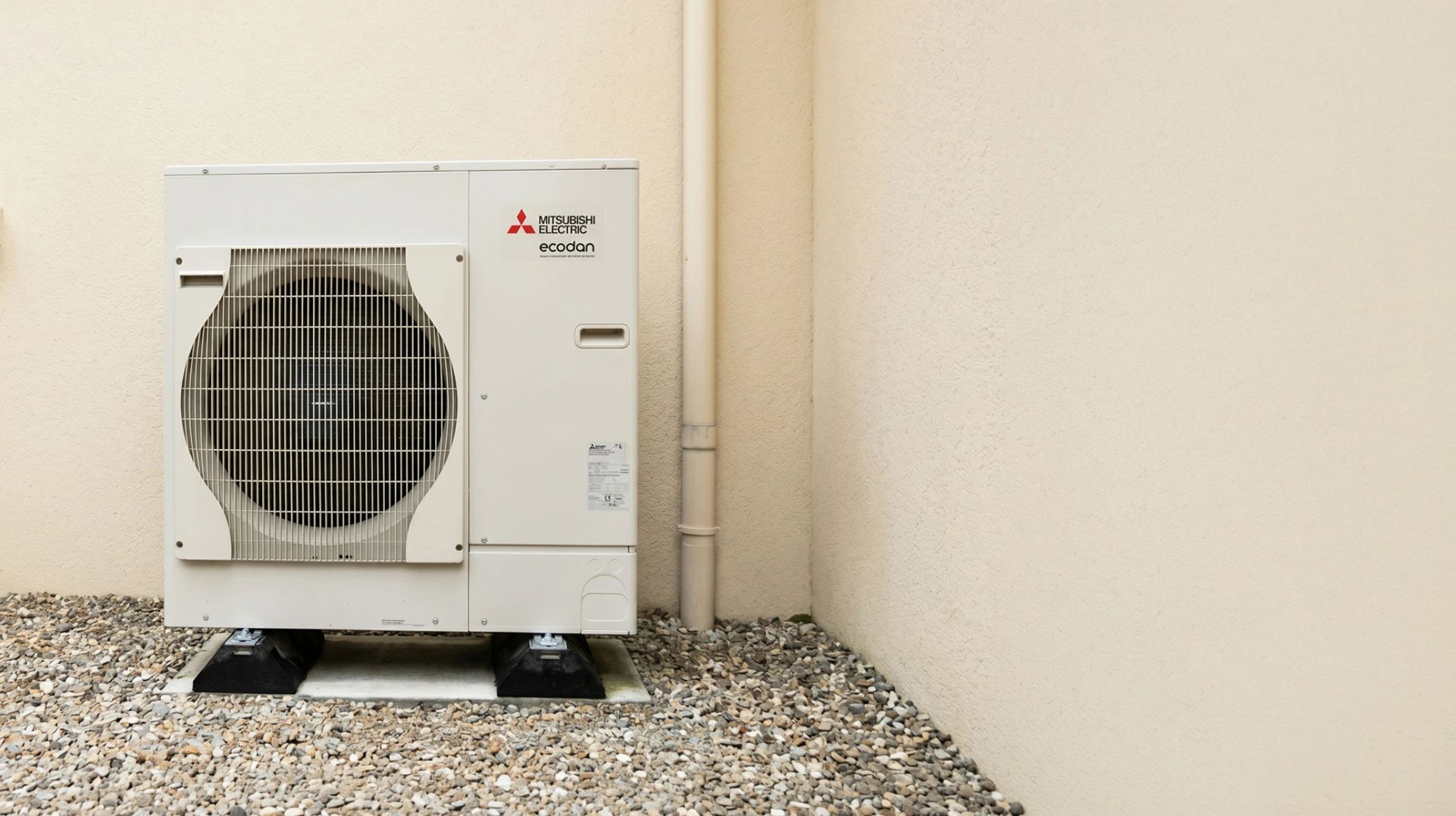 Extérieur résidentiel moderne avec pompe à chaleur air-eau installée sur socle béton contre façade blanche